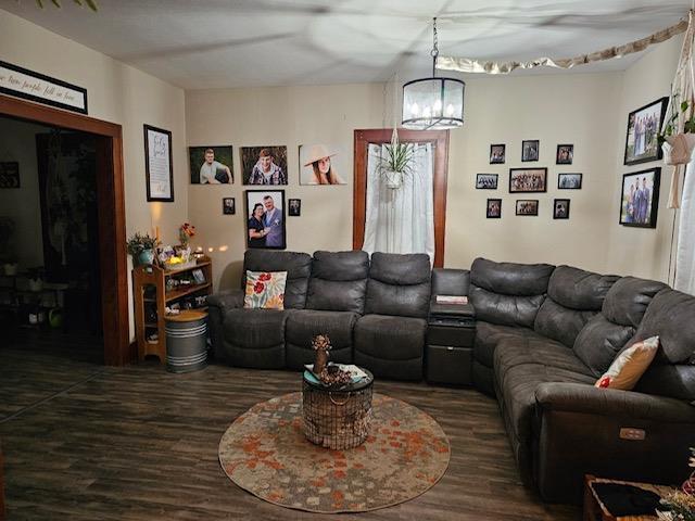 living room with dark hardwood / wood-style flooring and an inviting chandelier