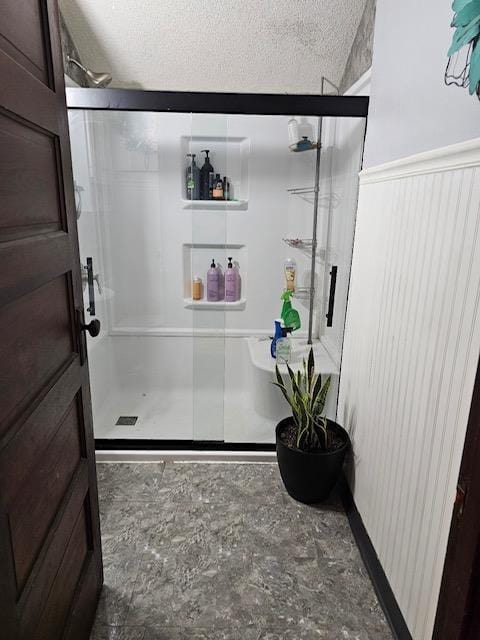 bathroom with a shower with shower door and a textured ceiling