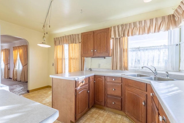 kitchen featuring kitchen peninsula, sink, and pendant lighting