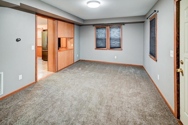 unfurnished bedroom with light carpet and stainless steel refrigerator