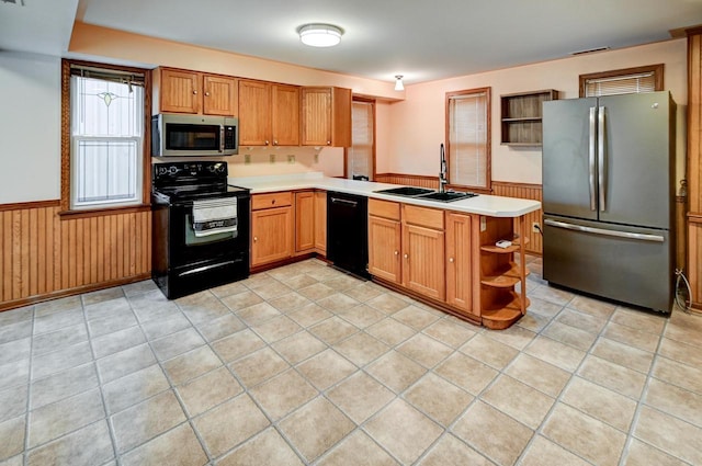 kitchen featuring black appliances, wood walls, kitchen peninsula, and sink