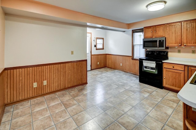 kitchen with electric range and wood walls