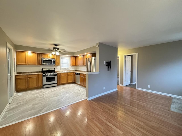 kitchen featuring stainless steel appliances, ceiling fan, light hardwood / wood-style floors, and sink