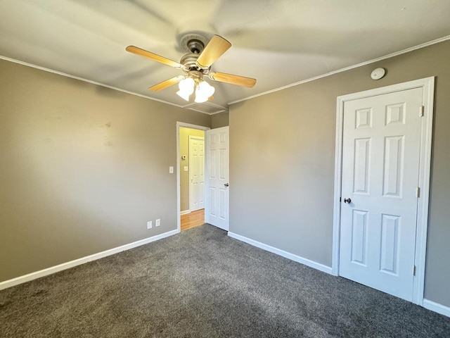 unfurnished bedroom with dark carpet, ceiling fan, and crown molding