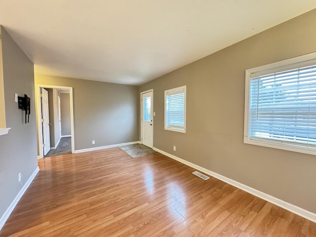 spare room featuring plenty of natural light and light hardwood / wood-style flooring