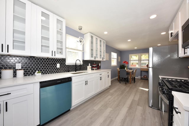 kitchen featuring white cabinets, gas stove, stainless steel dishwasher, and hanging light fixtures