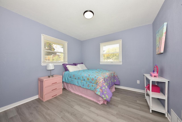 bedroom with hardwood / wood-style flooring and multiple windows