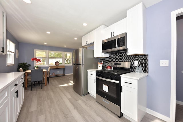 kitchen featuring backsplash, stainless steel appliances, white cabinetry, and light hardwood / wood-style flooring