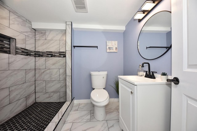 bathroom with tiled shower, vanity, and toilet