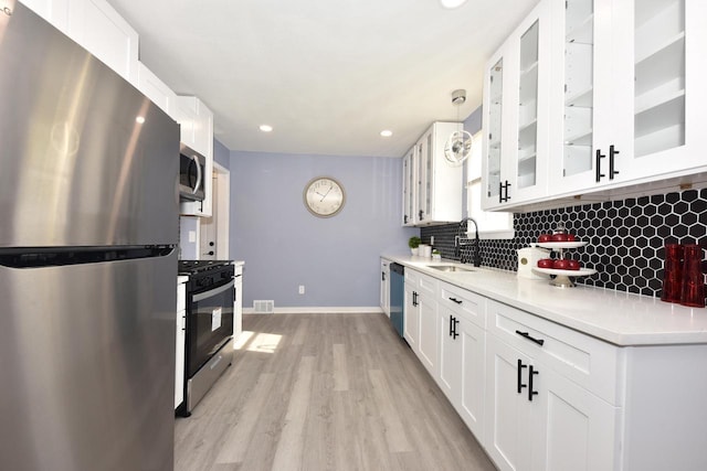 kitchen with stainless steel appliances, sink, pendant lighting, light hardwood / wood-style flooring, and white cabinets