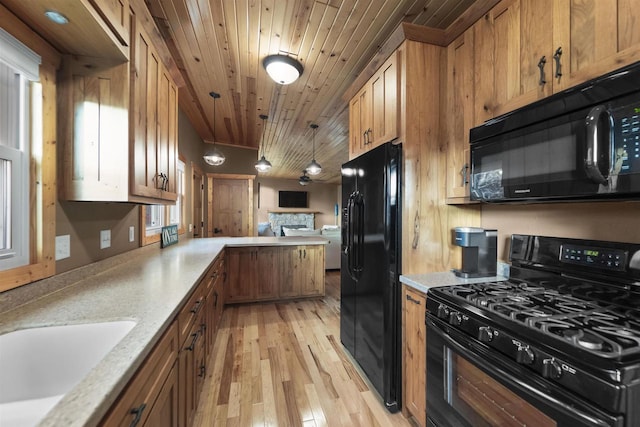 kitchen featuring wooden ceiling, hanging light fixtures, a stone fireplace, black appliances, and light wood-type flooring