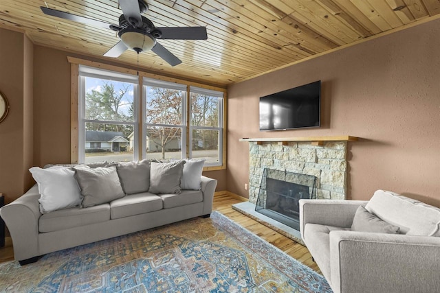 living room with ornamental molding, wood ceiling, ceiling fan, hardwood / wood-style flooring, and a fireplace