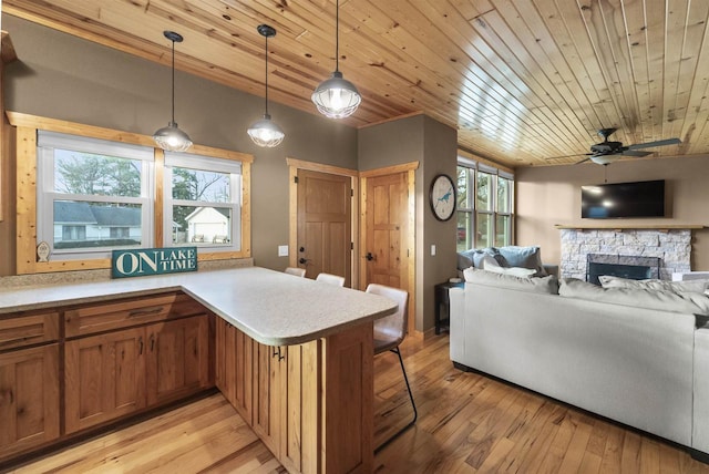 kitchen featuring kitchen peninsula, pendant lighting, light hardwood / wood-style flooring, and plenty of natural light