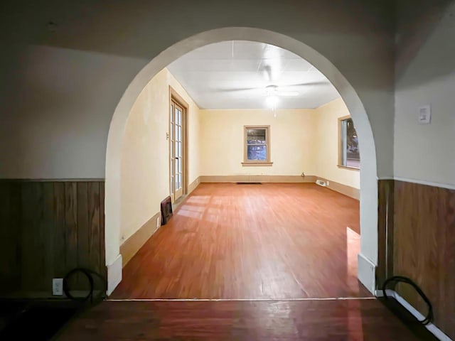 unfurnished room with hardwood / wood-style floors, ceiling fan, wood walls, and french doors