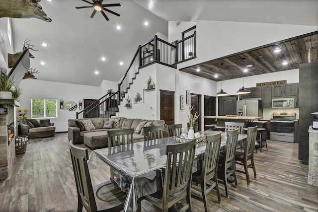 dining space with light hardwood / wood-style flooring, high vaulted ceiling, and ceiling fan