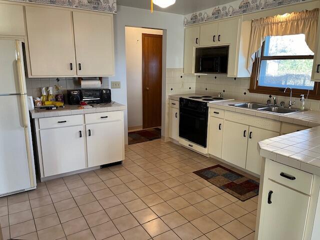 kitchen featuring tile countertops, white appliances, backsplash, sink, and light tile patterned flooring