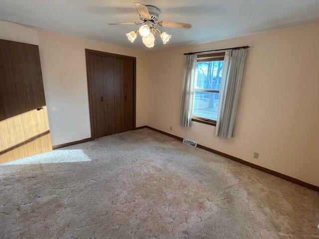 unfurnished bedroom featuring ceiling fan, a closet, and light colored carpet