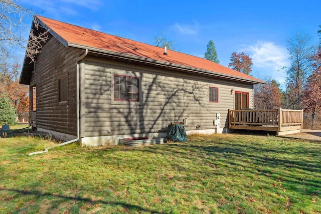 back of property featuring a wooden deck and a yard