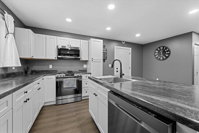 kitchen featuring white cabinets, appliances with stainless steel finishes, dark wood-type flooring, and sink