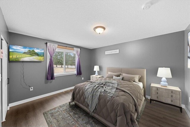 bedroom with a textured ceiling and dark hardwood / wood-style floors