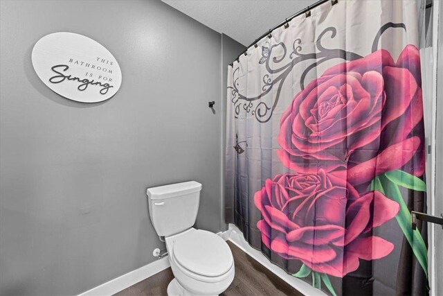 bathroom with curtained shower, hardwood / wood-style flooring, a textured ceiling, and toilet