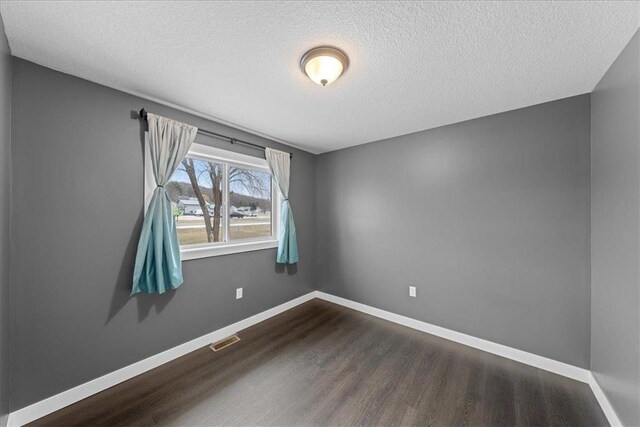 unfurnished room with dark wood-type flooring and a textured ceiling