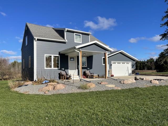 view of front of property featuring covered porch, a front yard, and a garage