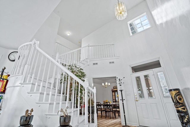 foyer featuring hardwood / wood-style floors, an inviting chandelier, and high vaulted ceiling