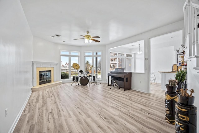 living room featuring ceiling fan, a fireplace, sink, and light wood-type flooring