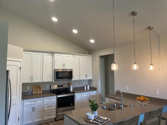 kitchen featuring stainless steel appliances, vaulted ceiling, sink, decorative light fixtures, and white cabinets