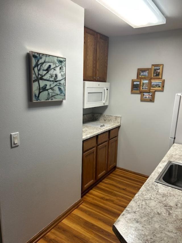 kitchen featuring sink, dark hardwood / wood-style floors, and white appliances