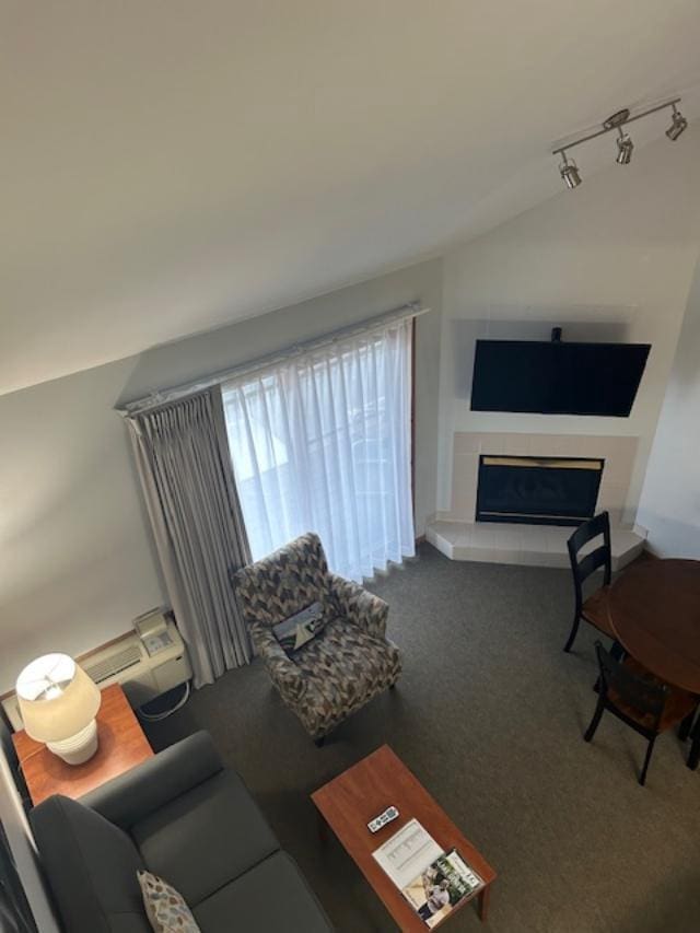 carpeted living room featuring a fireplace, track lighting, and vaulted ceiling