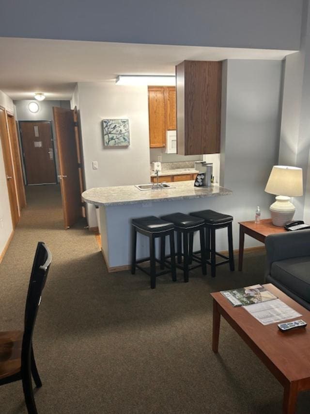 kitchen featuring kitchen peninsula, a breakfast bar, light colored carpet, and sink