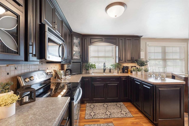 kitchen with backsplash, sink, appliances with stainless steel finishes, light hardwood / wood-style floors, and dark brown cabinetry