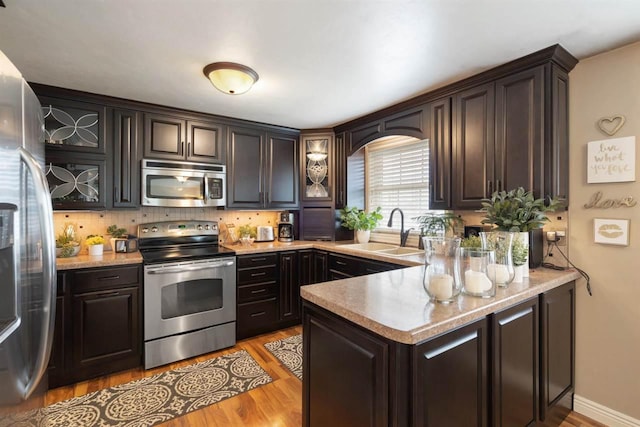 kitchen with sink, light hardwood / wood-style floors, dark brown cabinets, and appliances with stainless steel finishes