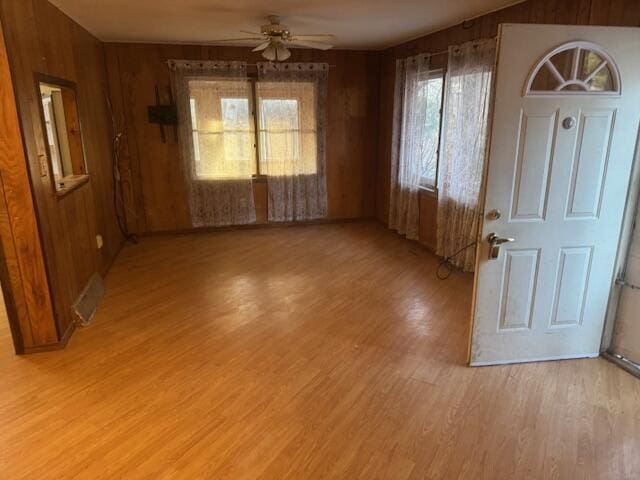 interior space featuring wooden walls, ceiling fan, and light wood-type flooring