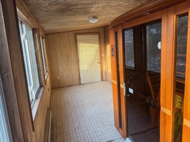 corridor featuring baseboard heating and wooden walls