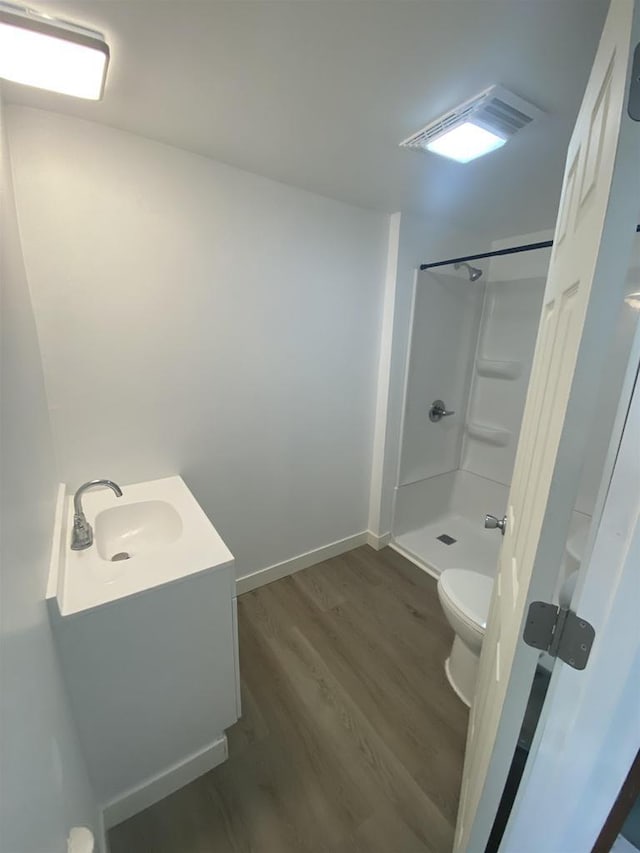 bathroom with hardwood / wood-style flooring, toilet, a shower, and vanity