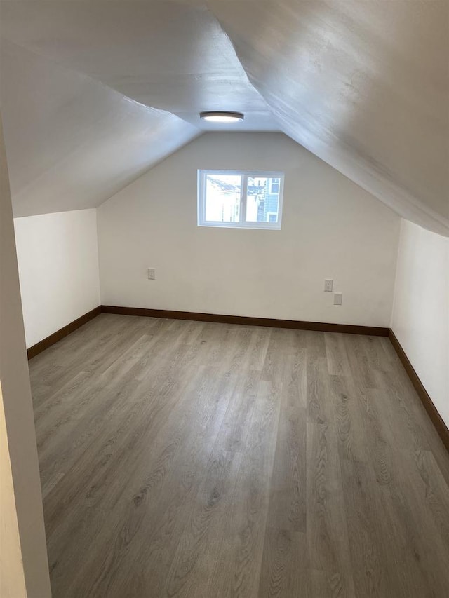 additional living space with hardwood / wood-style flooring and lofted ceiling