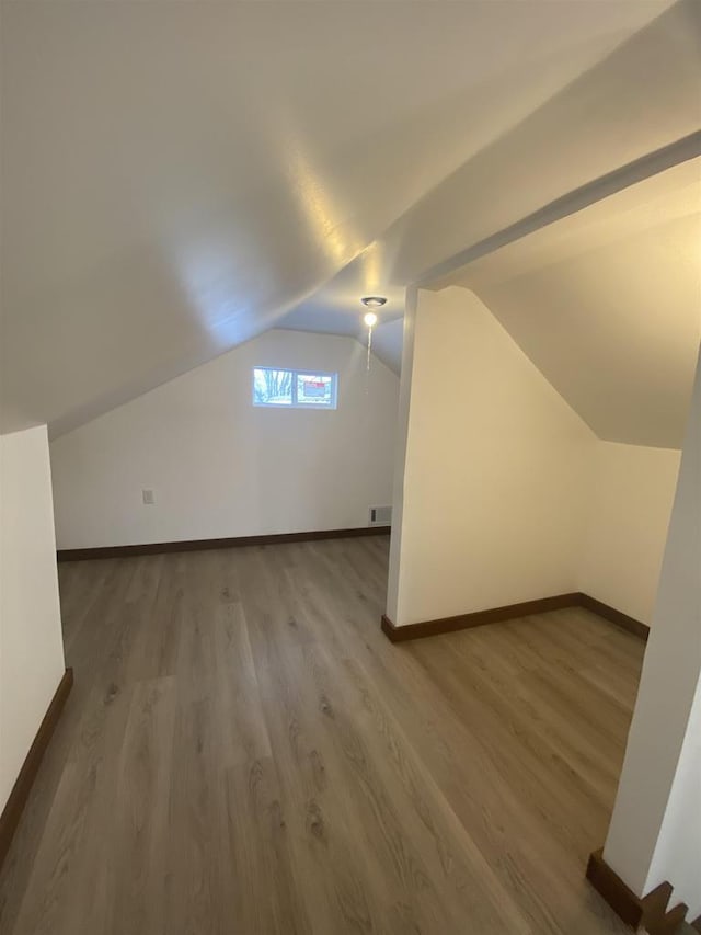 additional living space featuring hardwood / wood-style floors and vaulted ceiling