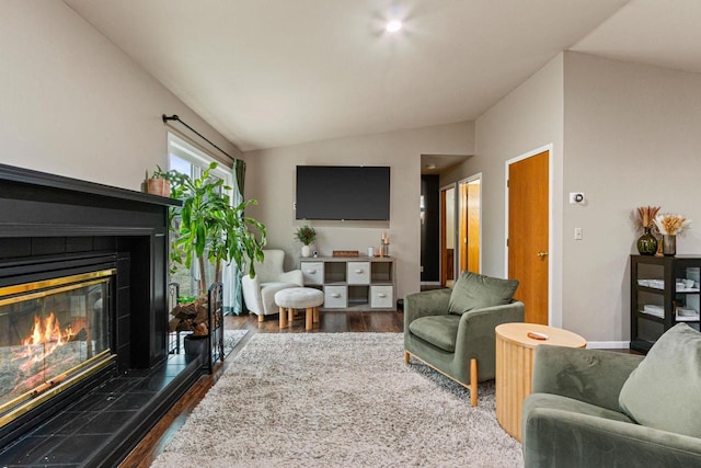 living room featuring a tile fireplace, dark hardwood / wood-style flooring, and vaulted ceiling