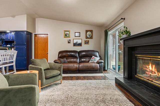 living room featuring dark hardwood / wood-style flooring, lofted ceiling, and a tiled fireplace