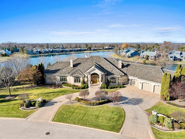 single story home featuring a front lawn, a water view, and a garage