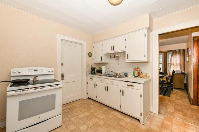 kitchen with electric range, white cabinets, sink, and tasteful backsplash