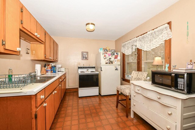 kitchen with sink, dark tile patterned flooring, and white appliances