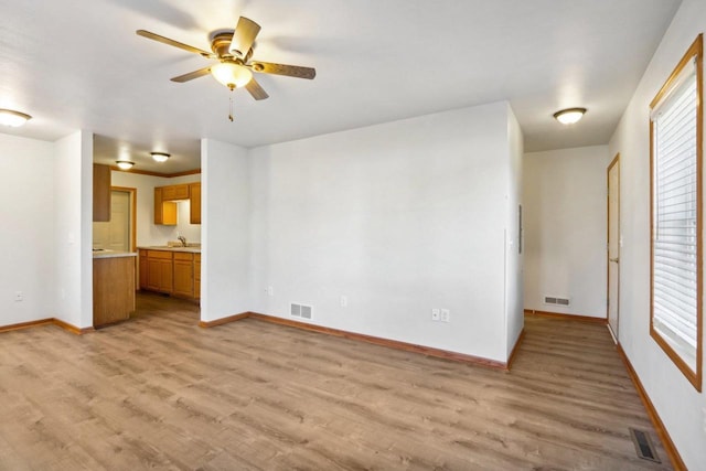 unfurnished living room with light wood-type flooring, ceiling fan, and sink