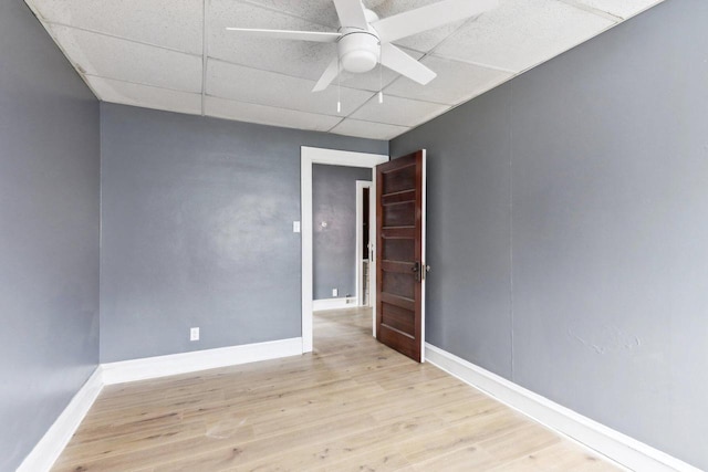 empty room featuring a drop ceiling, ceiling fan, and light wood-type flooring