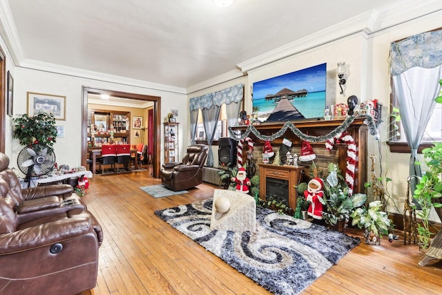 living room featuring hardwood / wood-style flooring, ornamental molding, and a brick fireplace