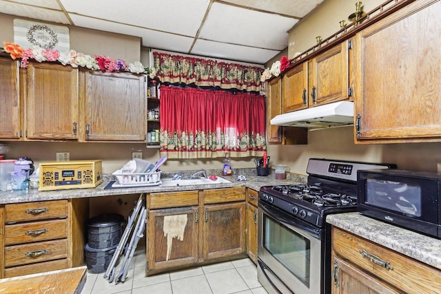 kitchen with a drop ceiling, light tile patterned floors, sink, and gas range