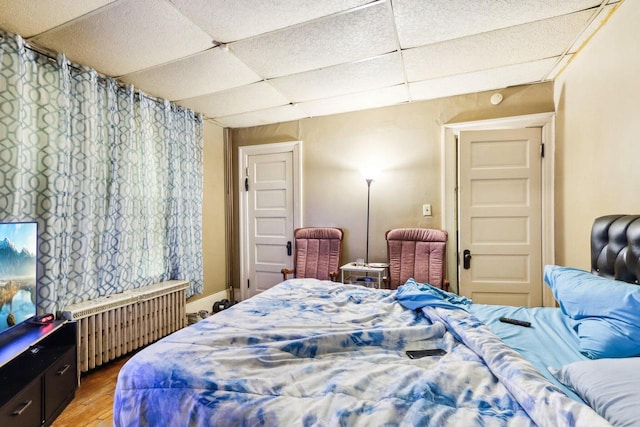 bedroom featuring radiator, a paneled ceiling, and wood-type flooring